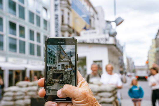 Person taking a photo with an iphone at Check Point Charlie in Berlin, Germany