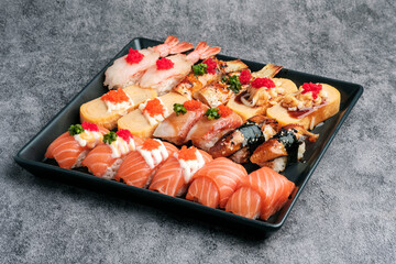 Variety of Sushi set Nigiri, served on black plate concept of a healthy diet.