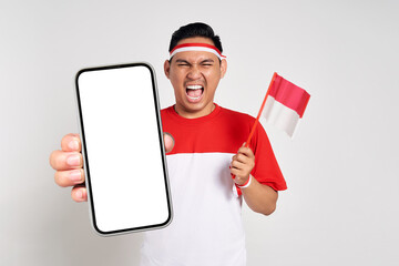 Excited young Asian men celebrate Indonesian independence day on 17 August while holding smartphone...