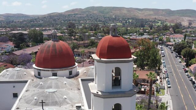 Panning aerial close-up shot of the belltower and dome of the Mission Basilica in San Juan Capistrano, California. 4K