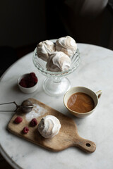 cup of coffee and zephyr on white table top view. coffee with white zephyr. sweets for breakfast	
