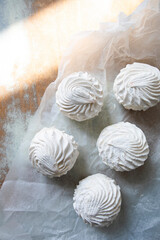 white zephyr closeup top view. vanilla marshmallow on crumpled parchment paper. marshmallows with sun glare.