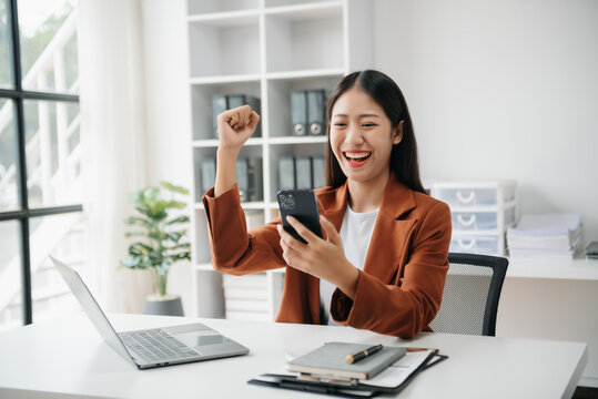 Asian business woman are delighted and happy with the work they do on their tablet, laptop and taking notes at the office..