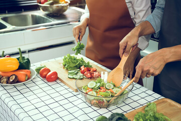 Asian couple enjoying cooking vegetable salad in the kitchen.