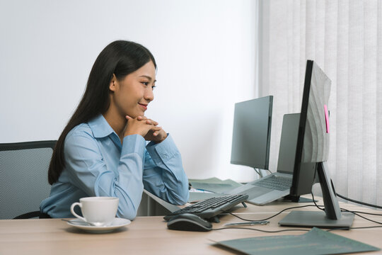 Asian woman software developers sitting in front of computers looking at computer codes on the screen.