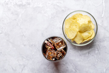 Refreshing glass of cola with ice, accompanied by a serving of crispy chips