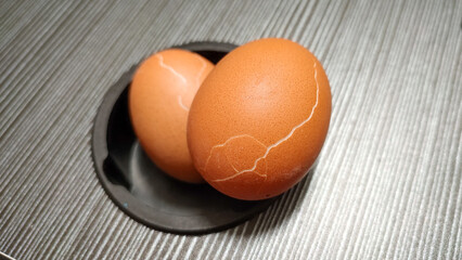 Cracked boiled chicken eggs on gray table, eggs are animal protein food