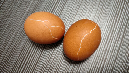 Cracked boiled chicken eggs on gray table, eggs are animal protein food