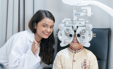 Ophthalmologist or optometrist or doctor doing eyes vision exam test for Indian child boy with...
