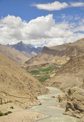 Scenic view of flowing river in between  rocky mountains with clouds in the sky on the way of Padum, Zanskar, Ladakh, INDIA 