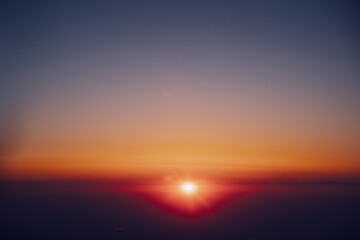 Obraz premium Sun Shining In Sunny Clear Sky Above Dark Horizon. View From Height Flight Of Plane. Bright Yellow, Orange And Magenta Colors Of Sunny Sky. High Attitude.