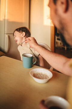 Boy refusing to eat porridge at dining table