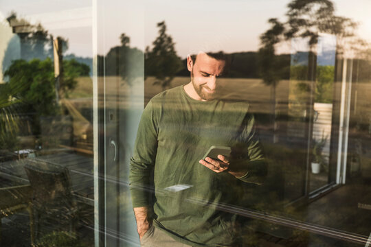 Man using smart phone seen through glass