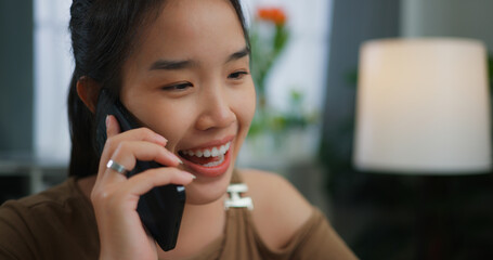 Asian happy cheerful young woman talking on the phone