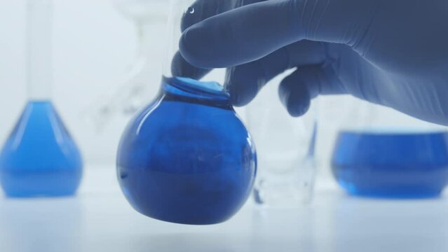 The flasks with blue liquid. Chemical reactions. Scientific experiment. Mix water and reagent. Lab conditions. Conical flask with blue liquid.