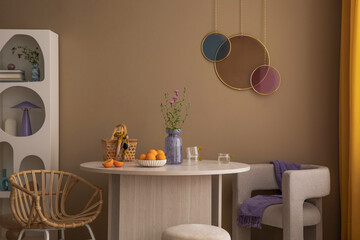 Warm and cozy living room interior with colorful ornament on wall, round table, gray armchair, modern rack, chair, orange curtain, brown wall, fruit and personal accessories. Home decor. Template.