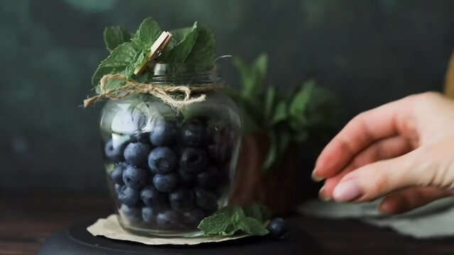 A jar of blueberries on the table and fresh mint leaves