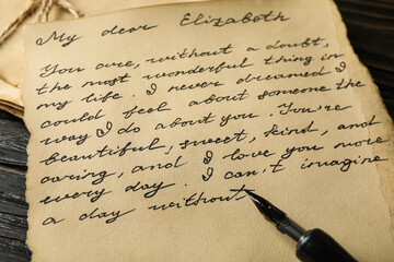 Old letter with text and pen on wooden background, close up