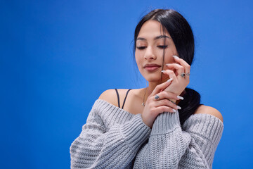 Portrait of the beautiful young brunette posing in the studio on a blue background