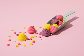 Jelly candies and scoop on pink background