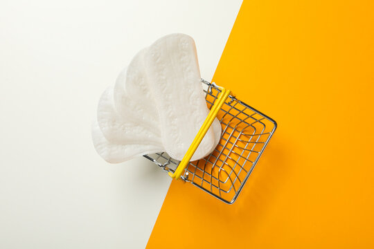 Menstrual pads in shopping cart on yellow and white background - Powered by Adobe