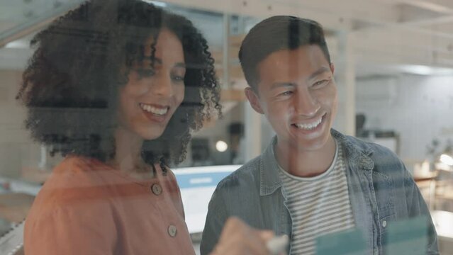 Business people, startup and writing on glass, night and laugh together for planning, innovation or brainstorming. Asian man, woman and moodboard with smile, partnership or copywriting in dark office
