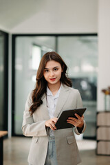 Confident business expert attractive smiling young woman holding digital tablet  on desk in creative office..