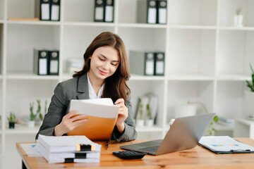 Woman freelancer is working her job on computer tablet and laptop Doing accounting analysis report real estate investment data, Financial at office.