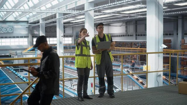 Sortation Fullfilment Center: Supervisor Talks with Specialist, they use Laptop to Optimize Package Order Delivery to Customers Worldwide. Conveyor Belt Logistics, Transportation Warehouse Facility