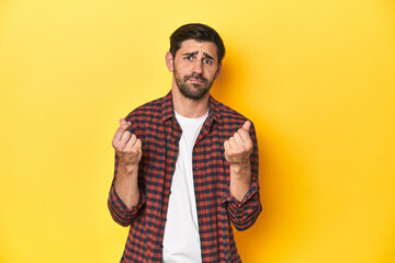 Caucasian man in red checkered shirt, yellow backdrop showing that she has no money.