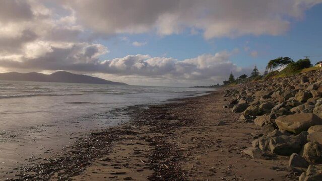 A panning shot taken on the beach of Paraparaumu New Zealand. The shot shows many stones and pans onto an island call Kapiti
