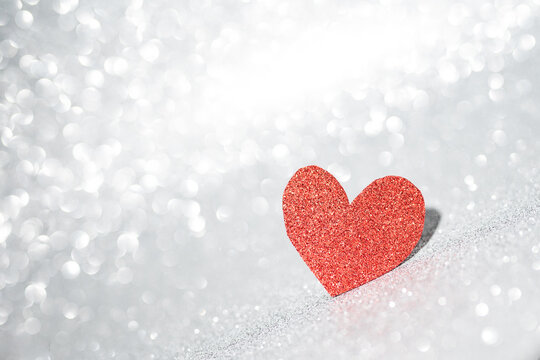 Red heart on a silver background with beautiful bokeh. Valentine's Day is the feast of lovers