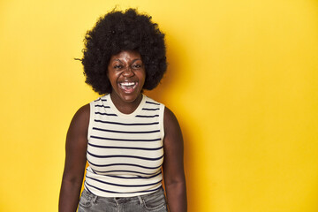 Fototapeta na wymiar African-American woman with afro, studio yellow background shouting very angry, rage concept, frustrated.
