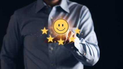 Businessman using a mobile phone to point to a smile face and five stars icon, representing...