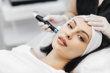 Professional dermatologist in medical gloves doing hydro peeling procedure for beautiful woman...
