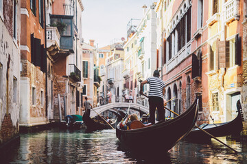 Fototapeta na wymiar Gondolier rowing gondola on canal in Venice, Italy.