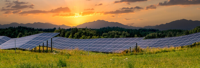 Panoramic view on solar panels and sunrise over the mountains at the distance - 624302820