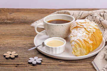 Good morning concept. Breakfast with cup of coffee and fresh croissant. Sweet creamy sauce