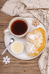 Good morning concept. Breakfast with cup of coffee and fresh croissant. Sweet creamy sauce