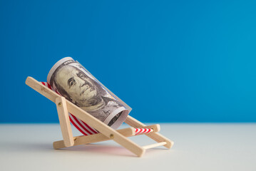 Happy US dollar bill banknote rest on wooden beach chair with blue background copy space in summer...