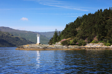 A white lighthouse stands on the banks of Loch Goil, Scotland. © Migara