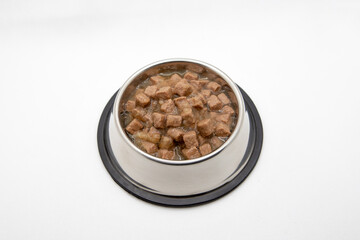 Wet cubical pieces pile isolated on white background. Bowl of meat dog food. Round metal bowl for pets with food.