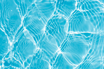 Blue water with ripples on the surface. Defocus blurred transparent blue colored clear calm water surface texture with splashes and bubbles. Water waves with shining pattern texture background.