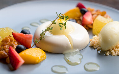 Panna cotta topping with yuzu orange sauce and side with ice cream, crumble, fresh strawberries,...