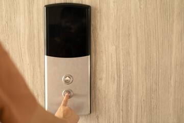 Woman finger pressing a down button of elevator button inside the building.