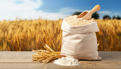 Ears of wheat and flour in bag on table on field background. Photo with copy space area for a text