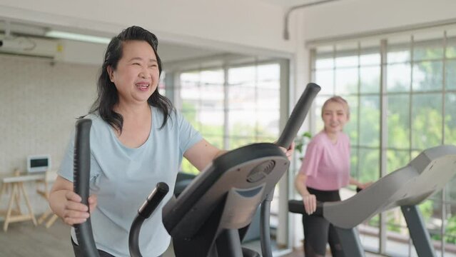 Happy elderly women and daughter enjoy exercising on the machine in living room at home on weekend. Elderly lifestyle, Famity activity