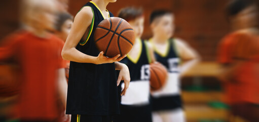 Basketball Dreams Unleashed: Young Boy Perfecting Skills on the Training Court. Basketball Kid Holding Ball During Practice Session. Basketball Background