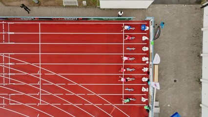 Obstacle course with running athletes on a tartan track. Drone move to the left