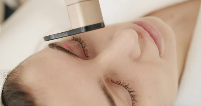 Beauty woman with protective glasses, aesthetic medicine is performing procedure. Close up of a young girl getting laser face treatment in a medical center, skin rejuvenation concept. Beauty treatment